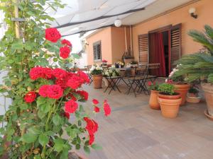 a patio with red flowers and tables and chairs at B&B il rosso e il nero in Zafferana Etnea