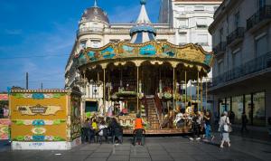 a group of people standing around a carousel in a city at Hôtel Royal in Montpellier