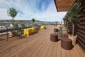 una terraza de madera con mesas y sillas amarillas en Scandic Flesland Airport en Bergen