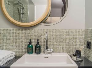 a bathroom with a sink, mirror, and soap dispenser at Hotel Norge by Scandic in Bergen