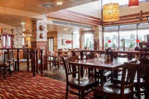 a restaurant with wooden tables and chairs and windows at Scandic Mikkeli in Mikkeli