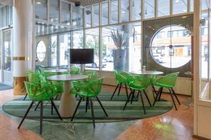 a room with green chairs and tables and a tv at Scandic Atrium in Turku