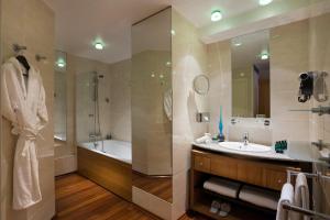 a bathroom with a tub, sink and mirror at Sofitel Biarritz Le Miramar Thalassa in Biarritz