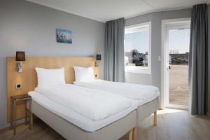 Un dormitorio con una gran cama blanca y una ventana en Scandic Vestfjord Lofoten, en Svolvær