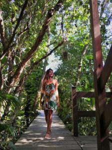 una mujer caminando sobre un puente de madera en el bosque en Pousada Estaleiro Village - Frente Mar, en Balneário Camboriú