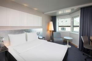 um quarto com uma cama branca, uma secretária e uma janela em Scandic Royal Stavanger em Stavanger