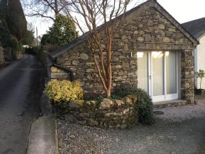 una casa in pietra con un albero in una finestra di Lowghyll suite a Bowness-on-Windermere