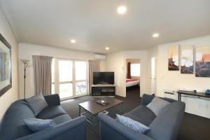 Sala de estar con 2 sofás azules y TV en Havelock North Motor Lodge en Havelock North