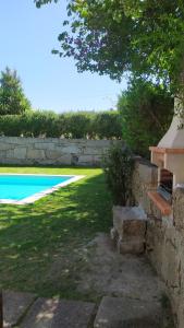un patio trasero con piscina y pared de piedra en Casa da Fonte - Boa Aldeia en Boa Aldeia