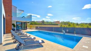 una piscina con tumbonas junto a un edificio en Eco-friendly Villa Aria with a pool and a party room, en Višnjan