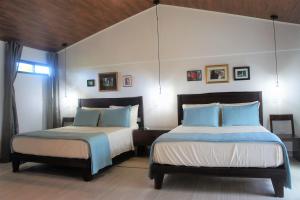 a bedroom with two beds with blue and white pillows at Casa Donna Rosa B&B in Nuevo Arenal