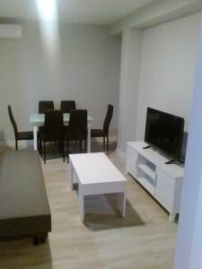 - un salon avec une télévision, une table et des chaises dans l'établissement GS ALCÁZAR, à Talavera de la Reina