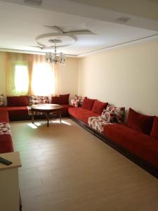 uma sala de estar com um sofá vermelho e uma mesa em residence akram m'diq em M'diq