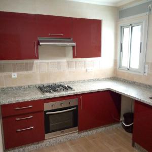 uma cozinha com armários vermelhos e um fogão em residence akram m'diq em M'diq