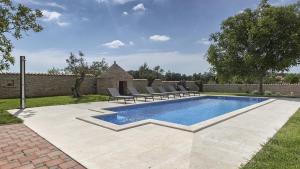 a swimming pool in a yard with lounge chairs around it at Villa Ive by Villas Holiday in Marčana