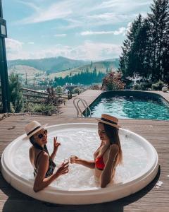 two women in bathing suits sitting in a pool at Stara Pravda Hotel in Bukovel