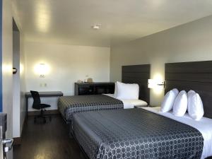 a hotel room with two beds and a desk at Sky Palace Inn By Jasper Near AT & T Center in San Antonio