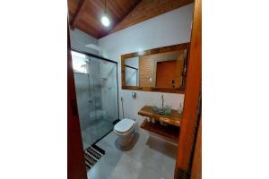 a bathroom with a toilet and a glass shower at Villa da Serra Ibitipoca chalé família in Conceição da Ibitipoca