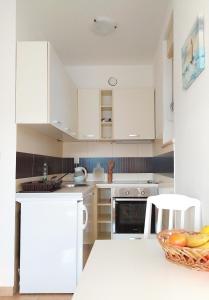 a kitchen with white cabinets and a bowl of fruit on the counter at Sunny Bay Apartments in Španjola