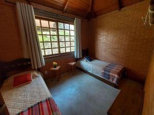 Una pequeña habitación con dos camas y una ventana. en Villa da Serra Ibitipoca chalé família - 700m do centrinho, en Conceição da Ibitipoca