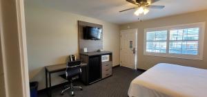 Schlafzimmer mit einem Bett, einem Schreibtisch und einem TV in der Unterkunft Beachwalker Inn & Suites in Pismo Beach
