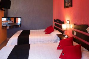 2 camas en una habitación de hotel con paredes rojas en Hotel Tepeyac, en San Cristóbal de Las Casas