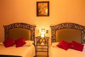 two beds in a hotel room with red pillows at Hotel Tepeyac in San Cristóbal de Las Casas