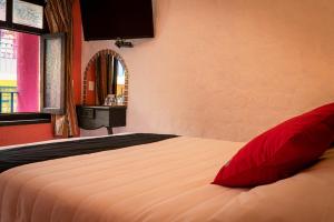 a bedroom with a bed with red pillows and a window at Hotel Tepeyac in San Cristóbal de Las Casas