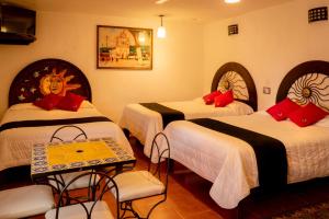 a hotel room with three beds and a table and chairs at Hotel Tepeyac in San Cristóbal de Las Casas