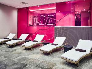 uma sala de espera com cadeiras brancas e iluminação rosa em Novotel Moscow Kievskaya em Moscovo