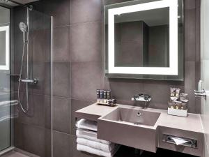 a bathroom with a sink and a shower and a mirror at Novotel Moscow Kievskaya in Moscow
