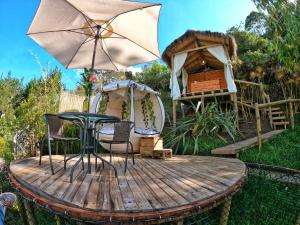 a wooden table with an umbrella on top of it at Levit Glamping - Hotel Guatapé ADULTS ONLY in Guatapé