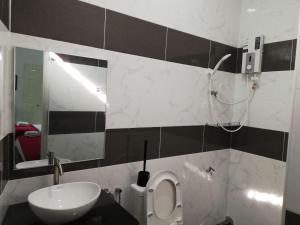 W łazience znajduje się umywalka, toaleta i lustro. w obiekcie RoomStay Hj Esmon Parit Raja UTHM w mieście Parit Raja