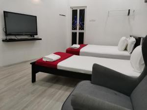 パリ・ラジャにあるRoomStay Hj Esmon Parit Raja UTHMのソファ、テレビが備わる客室のベッド2台