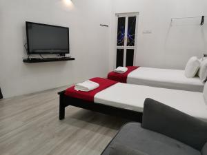 Habitación con 2 camas y TV de pantalla plana. en RoomStay Hj Esmon Parit Raja UTHM en Parit Raja
