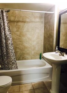 a bathroom with a tub and a sink and a toilet at Private Rooms NAIT Guest House For Men Only in Edmonton