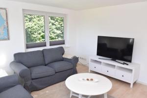 a living room with a couch and a tv and a table at fewo1846 - Solskin - ländlich gelegene Wohnung mit 2 Schlafzimmern in Flensburg