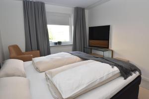 a bedroom with two beds and a flat screen tv at fewo1846 - FoerdeView - luxuriöse Wohnung mit 2 Schlafzimmern und Balkon mit Hafenblick in Flensburg