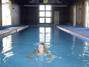 a woman is swimming in a swimming pool at Brassed Off Modern Arrowtown Studio in Arrowtown