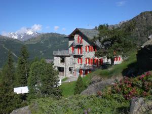 una casa en una colina con montañas en el fondo en Rifugio Zoia, en Chiesa in Valmalenco