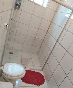 a bathroom with a toilet and a red rug at Pousada Aquarela Pirenopolis in Pirenópolis