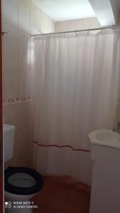 een badkamer met een wit douchegordijn en een toilet bij La posada del Nono in Villa Gesell