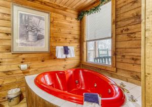 a red tub in a wooden bathroom with a window at A Waterfall Retreat- Waterfall, Cozy Cabin Retreat in the Smokies Comfort & Fun for All in Sevierville +22 photos