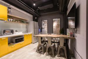 Taipei Sunny Hostel في تايبيه: مطبخ فيه دواليب صفراء وطاولة وكراسي