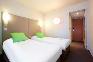 two beds in a hotel room with green pillows at Campanile Paris Est Bobigny in Bobigny