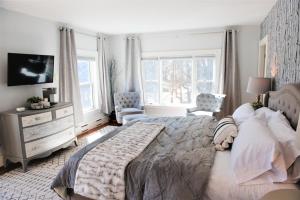 a bedroom with a large bed and a dresser and windows at Inn on Golden Pond in Holderness