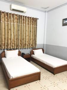 two beds in a room with a window at Huyen Tran Hotel in Can Tho