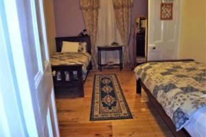 1 dormitorio con 2 camas y alfombra en Barossa Valley’s Captain Rodda’s Cottage en Angaston