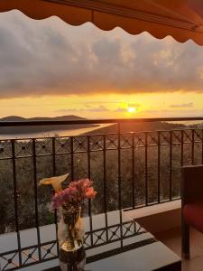 a view of a sunset from a balcony with a vase of flowers at Great View villa in Sivota
