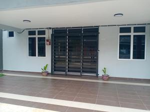 een wit gebouw met zwarte deuren en potplanten bij Kyra's Homestay Melaka in Merlimau